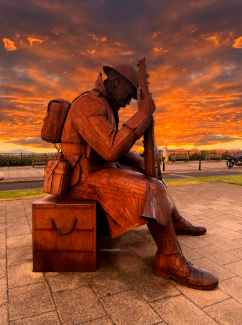 An iconic Seaham statue named 'Tommy' is sat in front of a cloudy and red sunset, looking resolute.